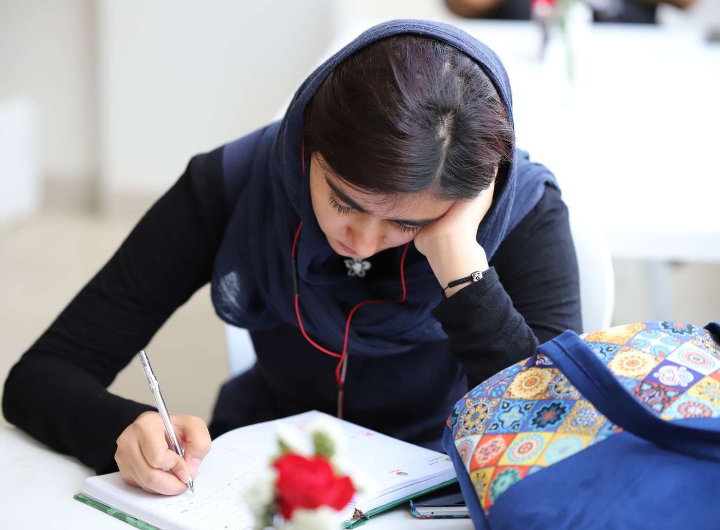 دختری جوان در حال نوشتن در دفتر یادداشت، با تمرکز کامل و در محیطی آموزشی – تصویری از صفحه اول وب‌سایت نیراویس، آکادمی آموزش داستان‌نویسی، ترجمه، فیلمنامه‌نویسی و خدمات ادبی بین‌المللی
